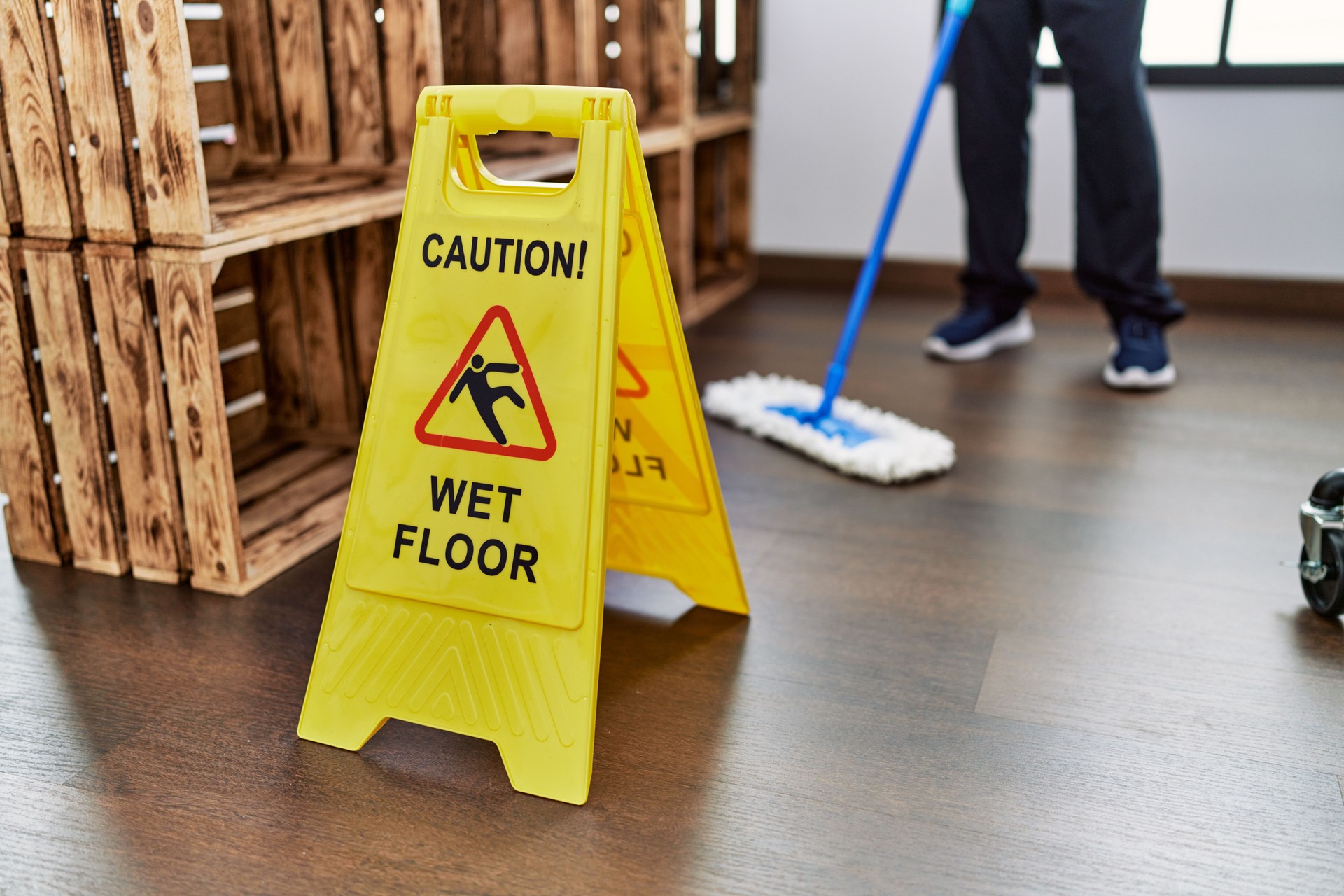 Middle age hispanic man cleaning floor with caution wet floor banner at home