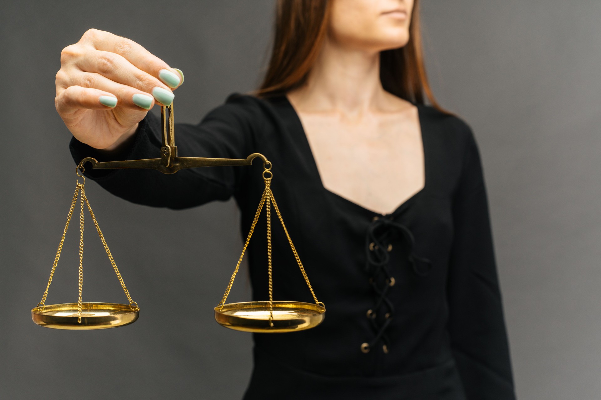 Mujer seria sosteniendo la balanza de la justicia sobre fondo oscuro