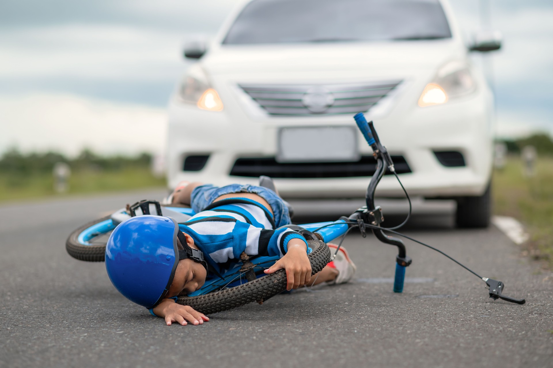 Un niño resultó herido porque su bicicleta chocó contra un automóvil en la carretera. Un niño asiático fue atropellado por un automóvil. El concepto de accidentes de tráfico y la reducción de accidentes por el uso de automóviles en la carretera. Enfoque selectivo.